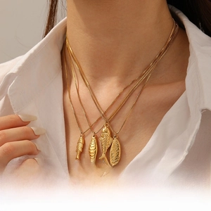 Detail of four gold-plated stainless steel fish pendant necklaces on a model neck