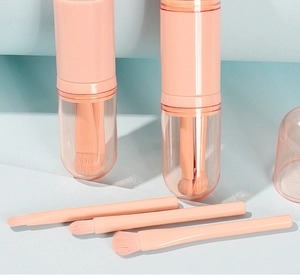Detail of pink-orange portable makeup brush set with a cylindrical storage case