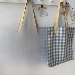 Detail von Gitter-Canvas-Tragetaschen mit Ledergriffen und verstärkten Metallnieten