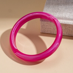 Detail of a pink acrylic round bangle with white ink marble texture on a jewelry box