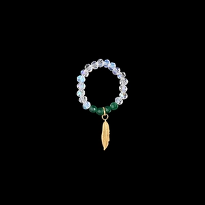 Close-up of elastic ring featuring faceted clear beads and a golden feather pendant