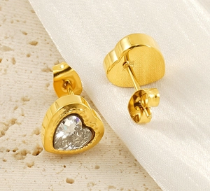 Detail view of heart-shaped gold studs with clear zircon on white silk background