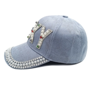 Détail du logo NY en perles et strass sur une casquette de baseball en suédine bleu clair