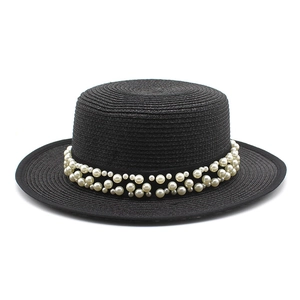 Dettaglio del cappello di paglia nero con elegante decorazione a doppia fila di perle