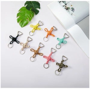 Flat lay of colorful braided paracord keychains with metal clips on a minimalist background