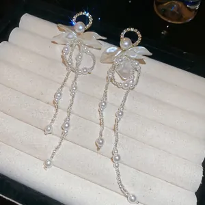 Elegant floral pearl tassel earrings with diamond accents on a jewelry display box
