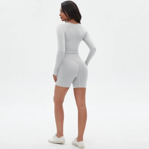 Detailansicht eines nahtlosen hellgrauen Yoga-Sets mit Langarm-Top und High-Waist-Sportshorts