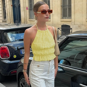 Dettaglio del top giallo a collo alto con pieghe eleganti e lacci sul retro