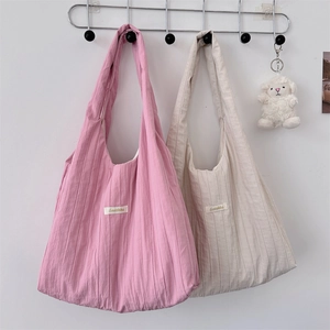 Close-up of pink and beige pleated fabric tote bags with textured vertical folds