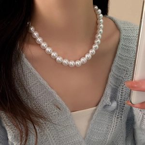 Gros plan d'un élégant collier de grandes perles porté au cou d'une femme chic