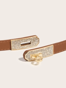 Detail of a slim brown leather belt with a gold rhinestone padlock buckle