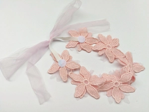 Dettaglio della fascia per neonata con fiori in pizzo rosa e nastri in morbido tulle