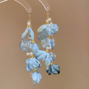 Détail de boucles d'oreilles à fleurs avec pétales en tissu bleu et perles sur crochets dorés