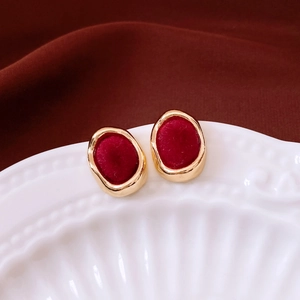 Macro shot of vintage deep red flocked earrings with gold metallic trim on ceramic