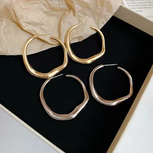 Irregular twisted circular hoop earrings in gold and silver finish on black display box