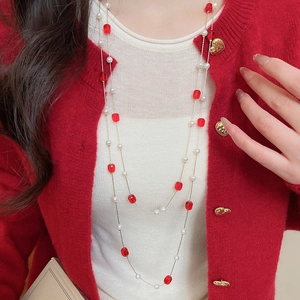 Detail of red crystal beads and white pearls on elegant layered gold necklace