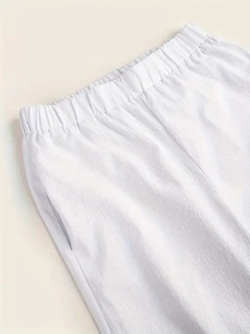 Gros plan détaillé sur la texture plissée blanche et la taille élastique du pantalon
