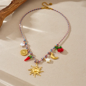 Colorful woven necklace featuring gold sun moon star and chili charms on sand background