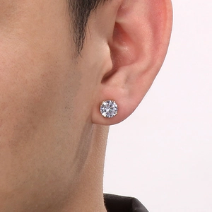 Close-up of a single gold-plated magnetic stud earring with a sparkling zircon on an ear