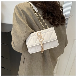 Detail of white quilted crossbody bag with golden SS logo and metallic fringe accents