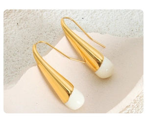 Macro shot of minimalist gold teardrop earrings with milky white enamel detail on stone