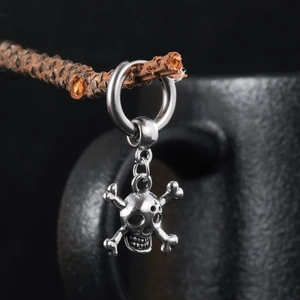 Gothic skull and crossbones pendant earring hanging on a rustic branch background