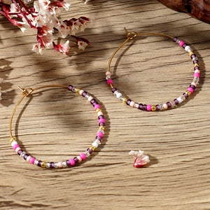 Detail of colorful Bohemian beaded hoop earrings displayed on a rustic wooden texture