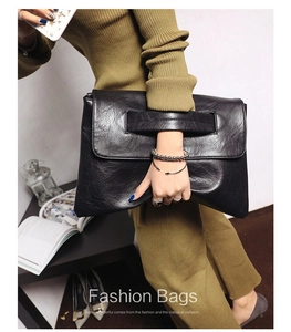 Close-up of black PU leather clutch bag with cutout handle and fine grain texture