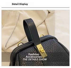 Detail shot of black crocodile texture leather handbag with golden metal twist lock closure