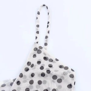 Close-up of thin straps and black polka dot mesh fabric on a white summer dress