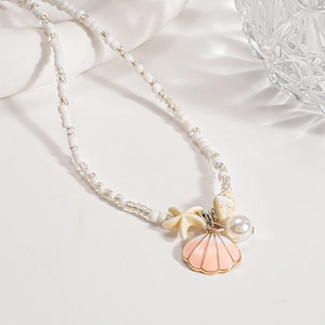 Detail of seashell and starfish charms on a white beaded beach vacation necklace