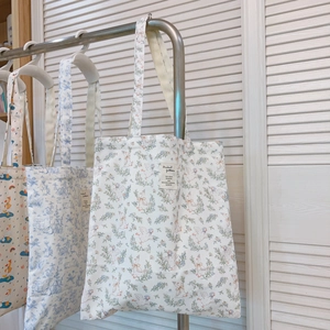 Detail von bedruckten Stofftaschen mit langen Griffen und schlichten Stoffetiketten