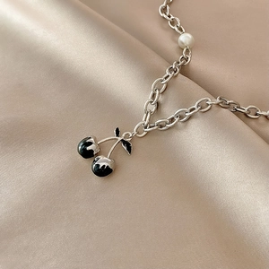 Detailed close-up of hip-hop chain necklace with black cherry pendant and white pearl accents