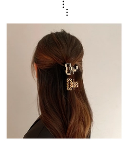 Detail of leopard checkerboard acetate hair clips styled in a half-up ponytail