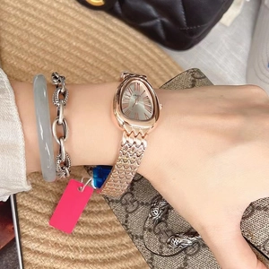 Detailed view of women's gold serpent head watch styled with jewelry and luxury accessories