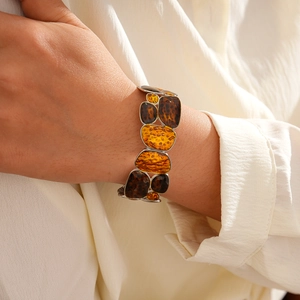 Detail of bohemian silver-tone cuff bracelet with amber resin geometric mosaic