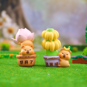 Macro shot of two resin capybara figurines with lotus and banana on a grassy base