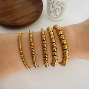 Set di cinque bracciali in acciaio al titanio placcati oro 18K con perline di varie misure