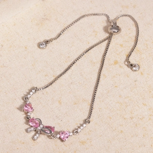 Detailed macro view of the silver bowknot bracelet with pink heart-shaped zircon stones