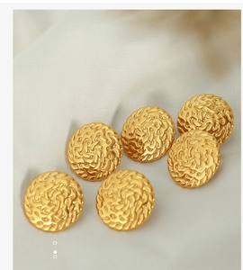 Detailed view of gold round earrings featuring intricate woven texture and vintage relief