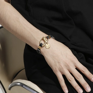 Détail de bracelet en cuir tressé noir double épaisseur et fermoir doré chic