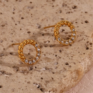 Macro detail of gold hoop earrings with twisted texture and sparkling zircon inlay