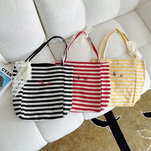 Detailed view of striped canvas tote bags with insect embroidery and lace bows