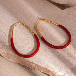 Detail of vintage oval drop hoop earrings with red enamel finish on gold plated metal