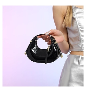 Detail of glossy black patent leather crescent bag with silver metallic studs in Y2K style