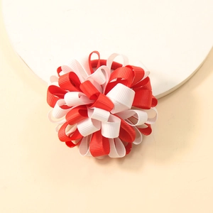 Detail of red and white grosgrain ribbon flower hair tie on a beige background