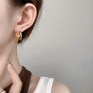 Nahaufnahme eines Models mit zweifarbigen gold-silbernen gedrehten Creolen