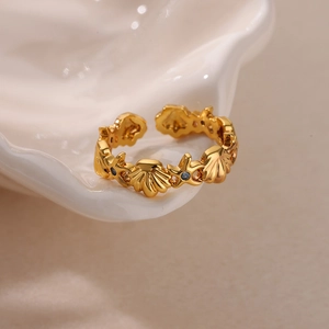 Detailed macro view of 18K gold starfishes and shell ring with blue gems on white ceramic