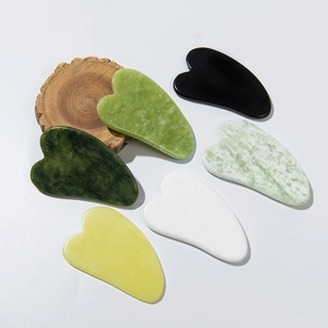 Set of heart-shaped natural jade gua sha massage tools in various colors on white background