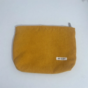 Detail of yellow corduroy makeup bag showing ribbed texture and May Rabbit brand label
